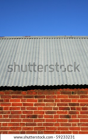 Corrugated iron roof on a red brick shed with a blue sky