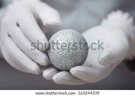 Human hands in warm mittens holding Christmas ball