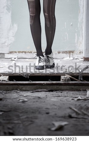 Human legs in stylish shoes standing in the ruined dirty room