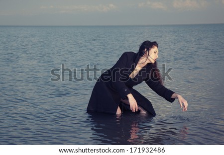 Lady in wet coat dancing in the sea