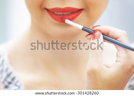 Woman applying red lipstick. Close-up view on face