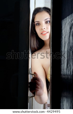 Standing curious woman opening door to answer the bell