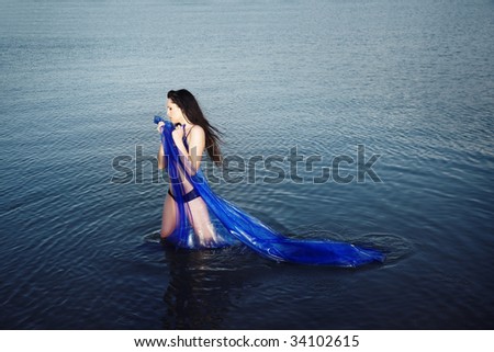 Sensual lady with blue fabric standing in the water