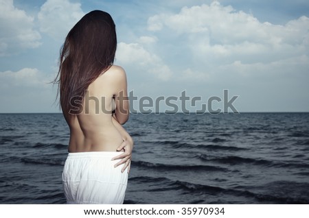 Rear view on a lonely woman with long hairs at the sea