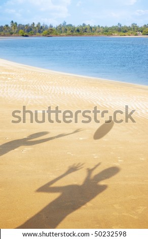 Shadows of two people playing with ball at the summer beach. Vertical photo with vibrant colors