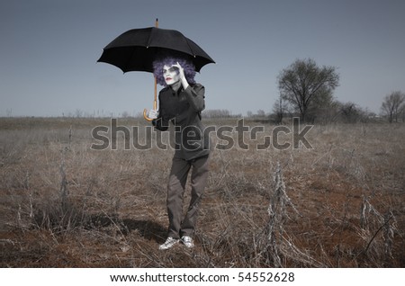 Funny man in the steppe holding umbrella and looking beyond the horizon. Artistic darkness and colors added