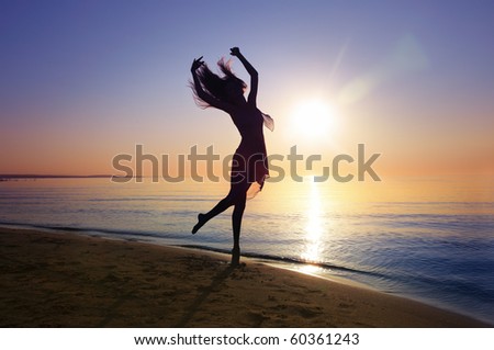 Silhouette of the woman dancing at the beach during beautiful sunset. Natural light and darkness. Artistic vivid colors added