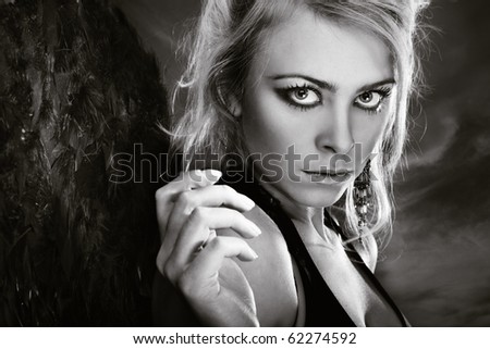 Sexy lady outdoors with perfect makeup. Black-and-white photo. Artistic darkness added