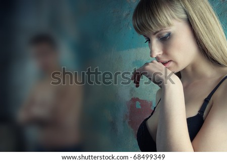 Sad woman indoors and defocused man as a symbol of relationship crisis