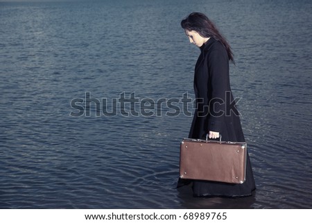 Side view on the lady holding case and going in the sea