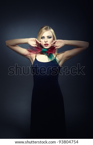 Model in stylish dress and scarf posing on a dark studio background