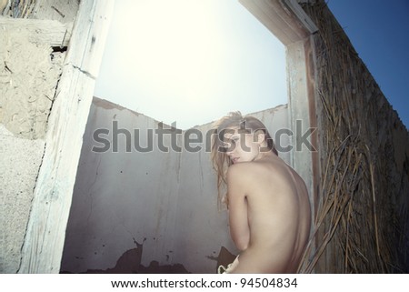 Sad single lady sits at the window of roofless house