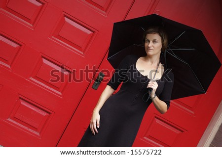 Woman with umbrella in front of red doors.