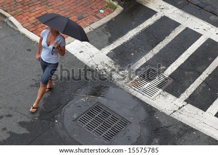 Woman walking in street with umbrella.
