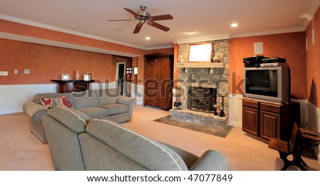 Wide angle view of a family room, with ceiling fan, couches, and fireplace. Horizontal format.