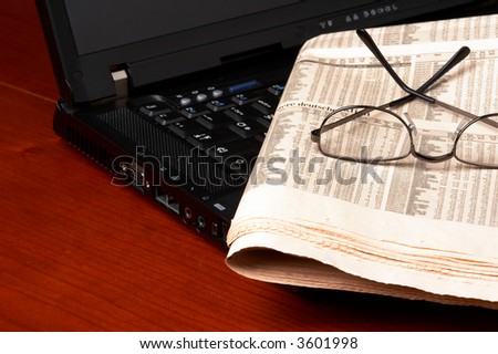Desk with laptop, newspaper, glasses