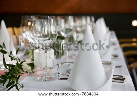 Well-laid table with white folded serviettes and wine glasses.