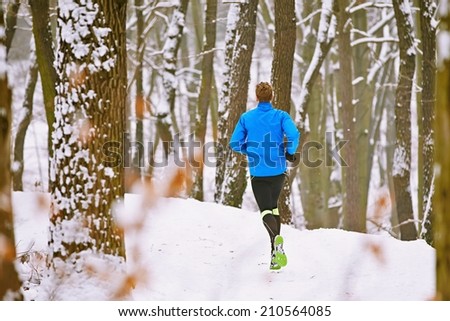 Young runner in winter jogging in forest