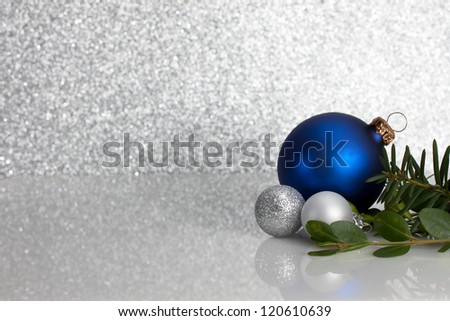 Blue and Silver ornaments with evergreens on glittery background