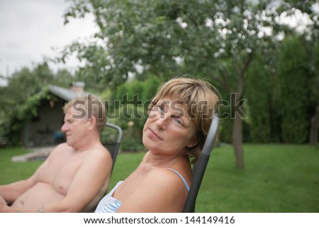 Mid-age woman and men sitting in the garden