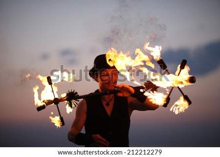 Fire dancer keeping balance of fire torch; fire show tricks
