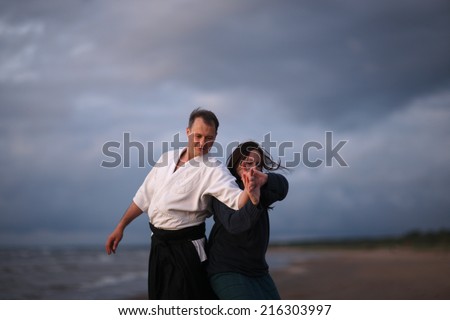 Practicing Japanese martial arts on the beach; woman doing self-defense technique