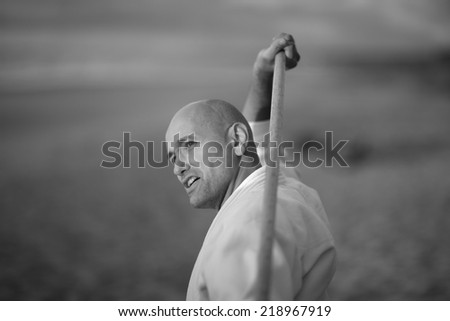 Portrait of martial arts practitioner using short staff, monochrome