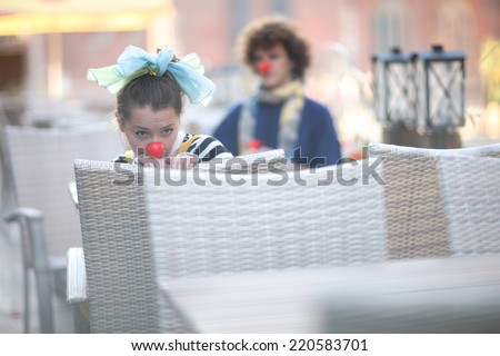 Clown girl waiting for dinner in street cafe, street theater concept