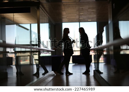 Silhouettes of talking women in the office corridor