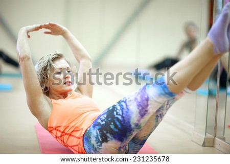 Middle age woman doing push press technique; elevated arms and legs