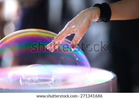 A magician pushing her hand through the bubble wall