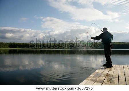 man sanding on pier handling fishing nets