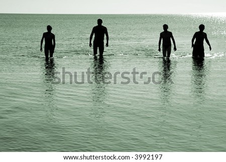 silhouette of four men walking out of water