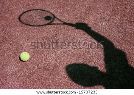 Shadow of a player over red tennis court