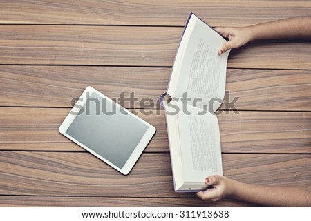 Book and digital tablet on a wooden table