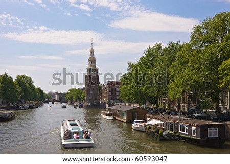 A canal cruise boat sails towards the Montelbaan Tower in Amsterdam
