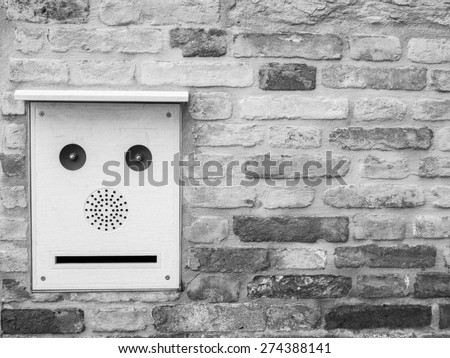 Black and white image of an building intercom that resembles a robot face