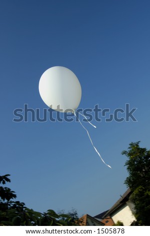 A child\'s balloon floats away into a clear blue summer sky. Space for text in the sky.