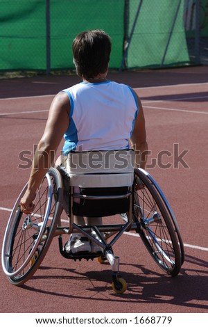 A wheelchair athlete taking a moment\'s pause during a tennis championship match. Her tennis racquet can just be seen in her right hand and a little sweat on the back of her blouse.