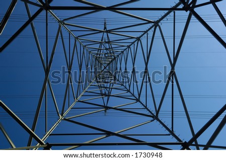 Inside an electricity pylon looking directly up at the clear blue sky. It is as if the pylon forms a metal spider\'s web. A tiny aeroplane seems to be caught in the bottom left corner.