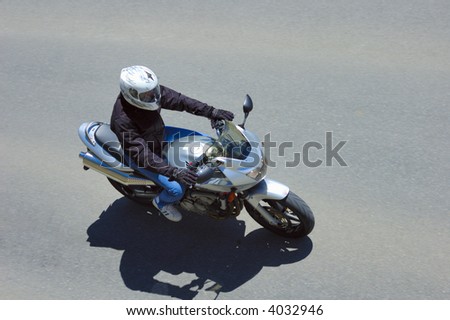 A motorcyclist in action, taken from above. Motion blur on the tarmac of the road. Space for text in image.