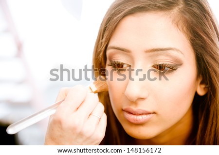 Attractive young asian indian woman having her make up done by a make up artist