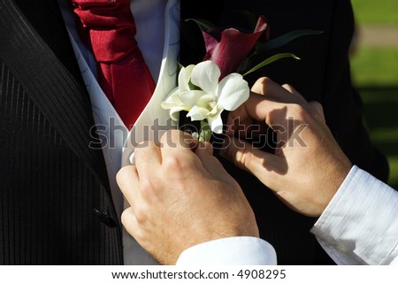 Best man places corsage on groom at weeding