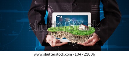 Young businessman presenting a perfect ecology land with a house and windmills