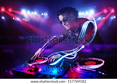 Handsome disc jockey playing music with light beam effects on stage