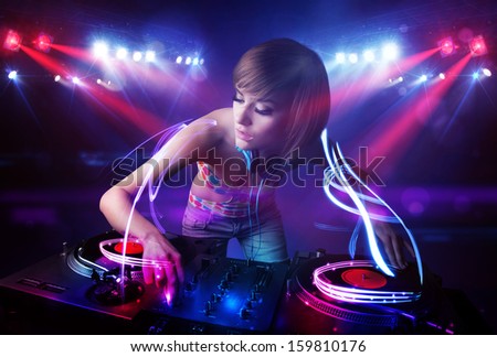 Pretty young disc jockey girl playing music with light beam effects on stage