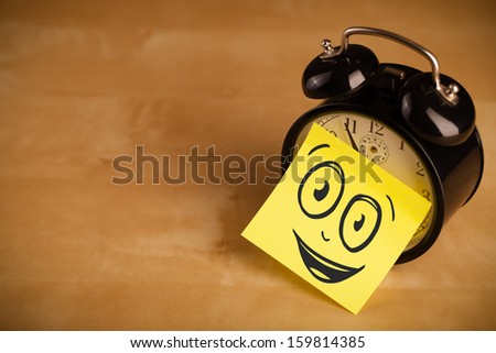 Drawn smiley face on a post-it note sticked on an alarm clock