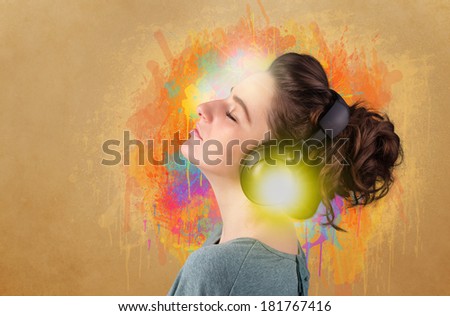 Pretty young woman with headphones listening to music in front of a painted wall