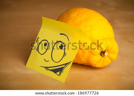 Drawn smiley face on a post-it note sticked on a lemon
