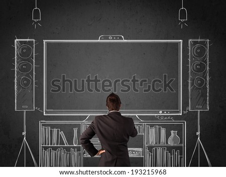 Young businessman standing and enjoying home cinema system sketched on a chalkboard